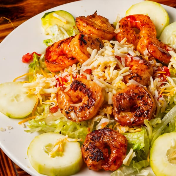 El Mezcal Mexican Restaurant's grilled shrimp salad with shredded cheese, lettuce, and cucumber slices.