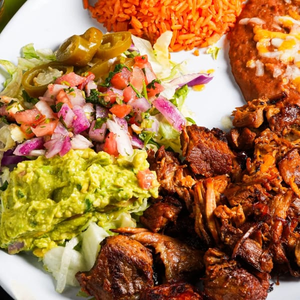 El Mezcal Mexican Restaurant's carnitas plate with rice, refried beans, guacamole, pico de gallo, and jalapeños.