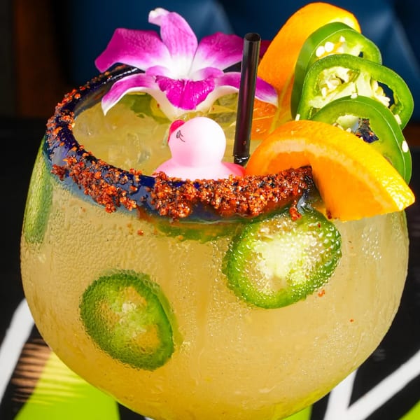 Spicy El Mezcal margarita with a pink rubber duck, orange slices, jalapeños, and a purple orchid.