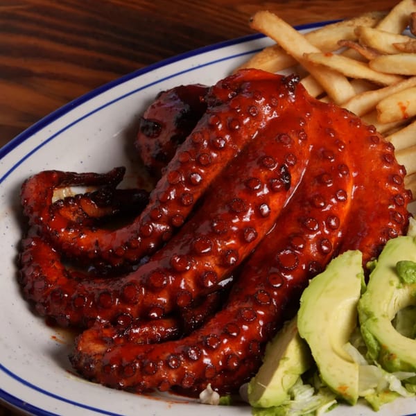 El Mezcal's grilled octopus with a red sauce, served with french fries and sliced avocado.