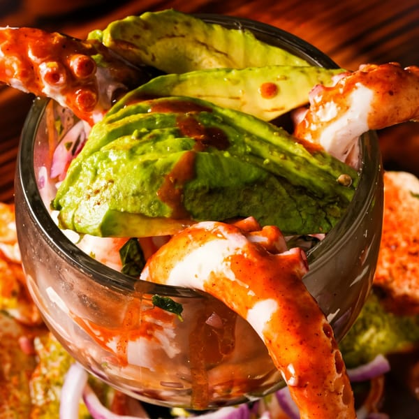 El Mezcal Mexican Restaurant's octopus cocktail with avocado slices and red sauce in a glass.